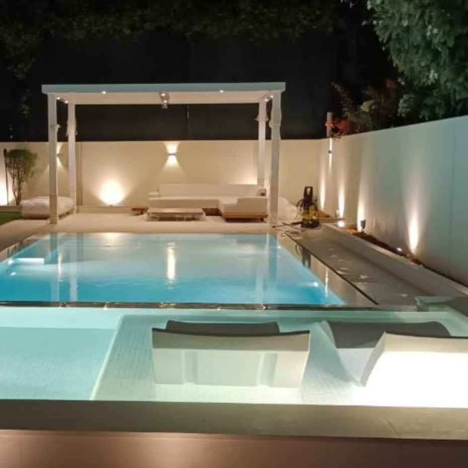 A Night View Of A Swimming Pool Featuring 500 White Glass Mosaic Pool Tiles.