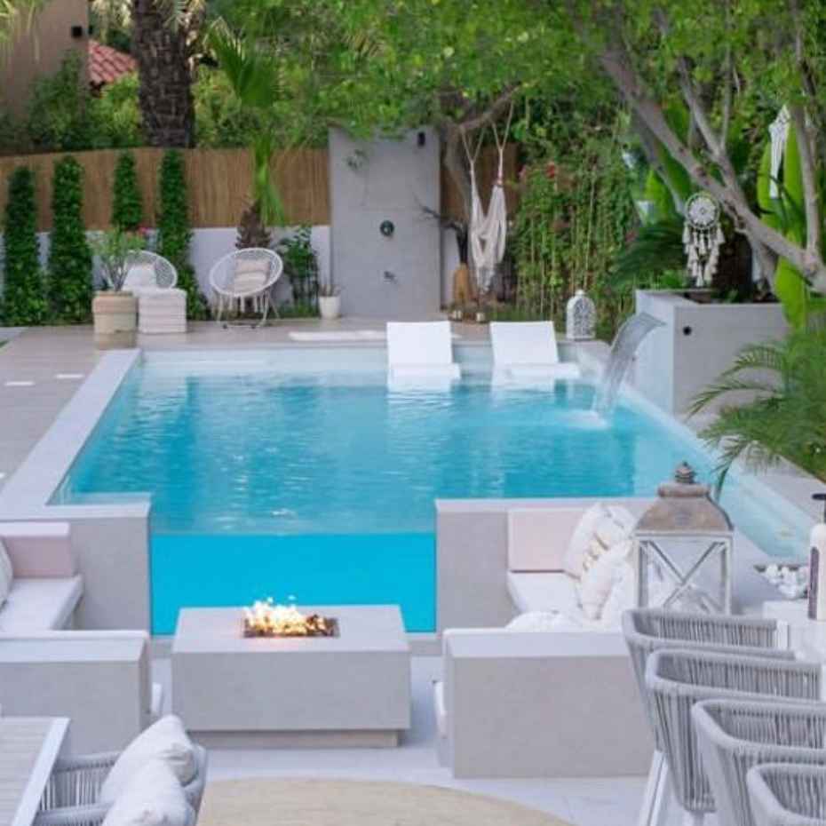 An Outdoor Swimming Pool With 500 White Glass Mosaic Tiles, Surrounded By Comfortable Seating Areas And Lush Greenery