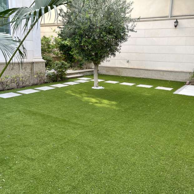 Outdoor Area With Artificial Grass, Tiled Sidewalk, And A Corner Tree, Creating An Elegant Look With Synthetic Grass In Dubai