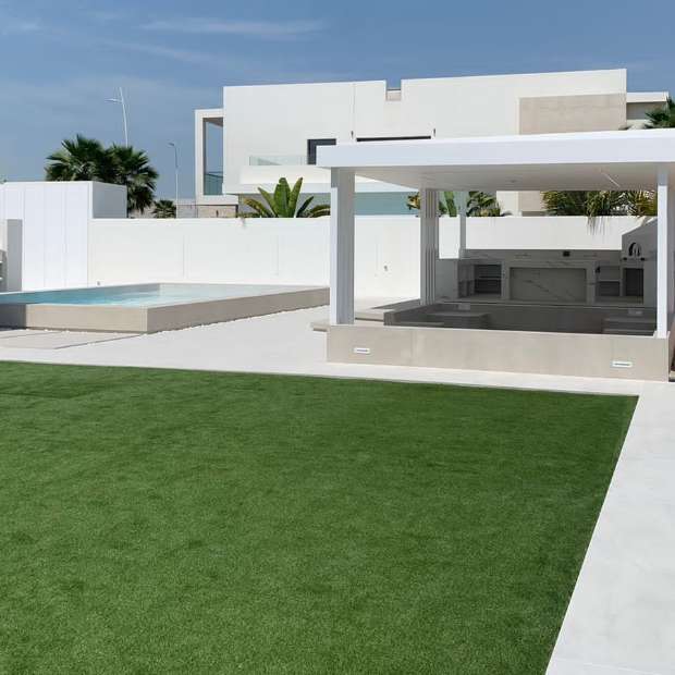Outdoor Area With Artificial Grass, Tiled Sidewalk, And A Corner Tree, Creating An Elegant Look With Synthetic Grass In Dubai, UAE