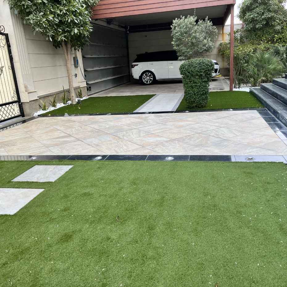 Adjacent Car Porch Area With Artificial Grass Enhancing The Elegant House Entrance.