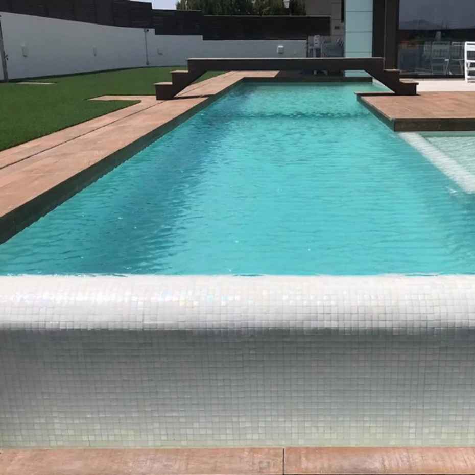 Front View Of A Beautiful Swimming Pool With EGM-Pearl 500 Mosaic Tiles With A Connecting Bridge Across The Pool.