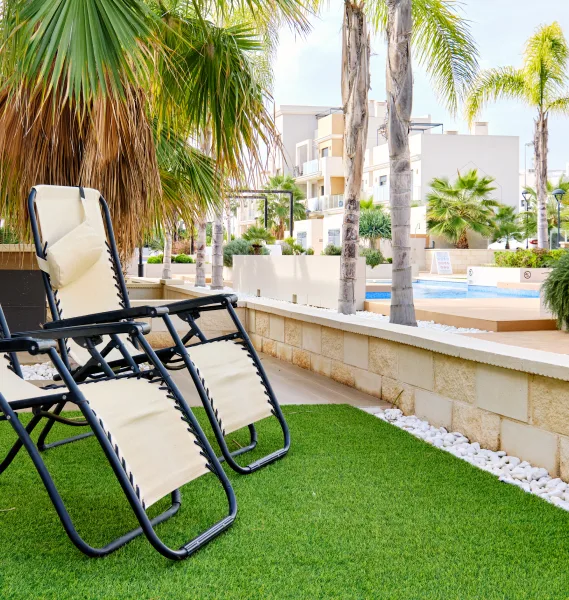 Two chairs on artificial grass beside a pool