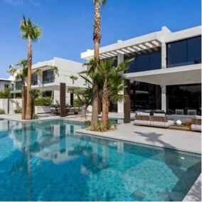 Modern villa with palm trees reflected in clear swimming pool using textured pool tiles around deck