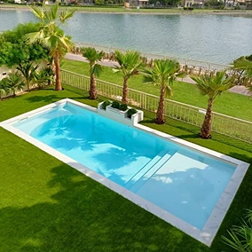 Rectangular backyard pool with palm trees and grass showcasing clean tiles of swimming pool finish