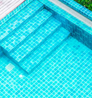 Blue ceramic tiles for a pool with steps, featuring clean lines in a sunny outdoor setting.